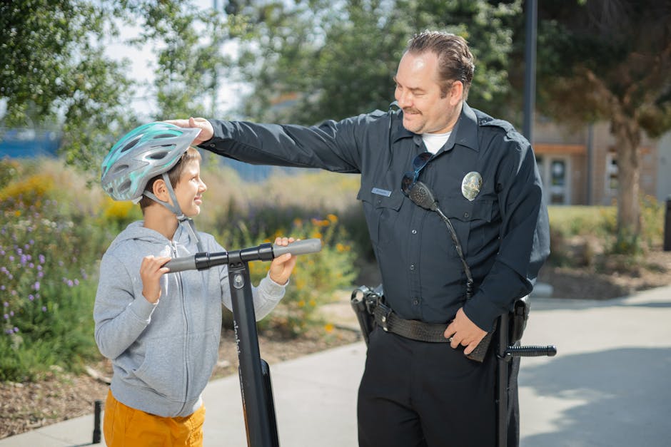 A friendly officer interacts with a child wearing a helmet outdoors, showing community support.